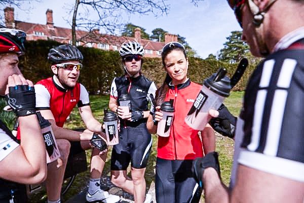 A group of road cyclists taking a break and hydrating themselves. 